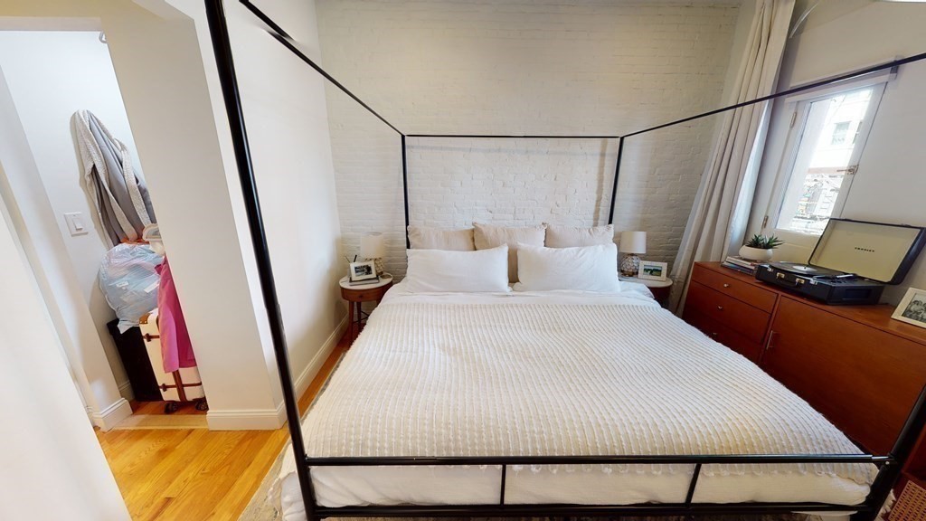 27 Bowdoin Street, Unit 1B Boston, MA 02114 - Photo 17 of 18 a bedroom with a bed a mirror on the wall and a large window