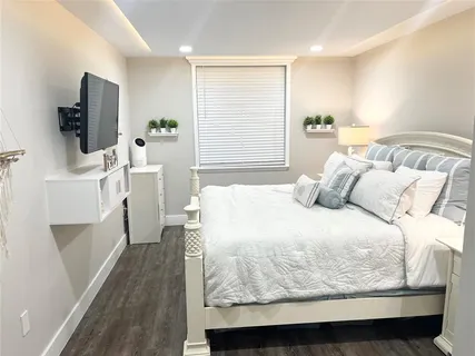 a bed sitting in a bedroom next to a window with a flat screen tv