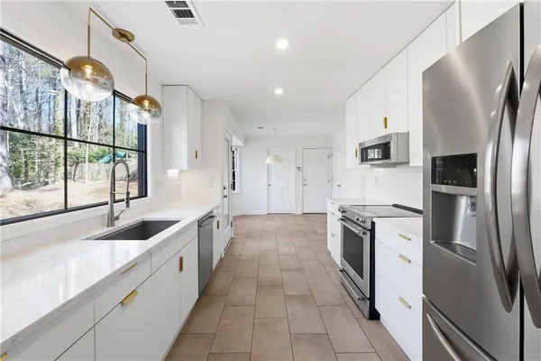 a kitchen with stainless steel appliances granite countertop a refrigerator a sink a stove and a refrigerator