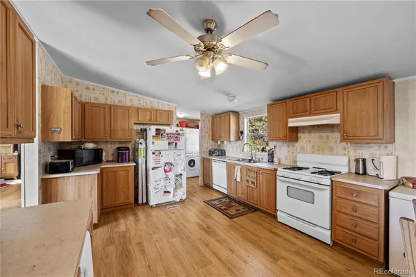 a kitchen with stainless steel appliances a stove a sink dishwasher a refrigerator cabinets and wooden floor