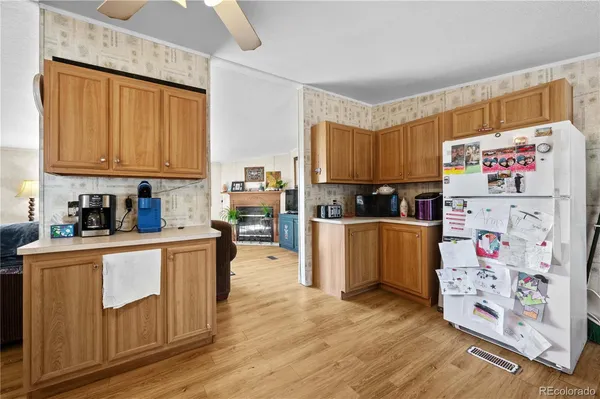 a kitchen with granite countertop a refrigerator a stove a sink dishwasher and wooden cabinets