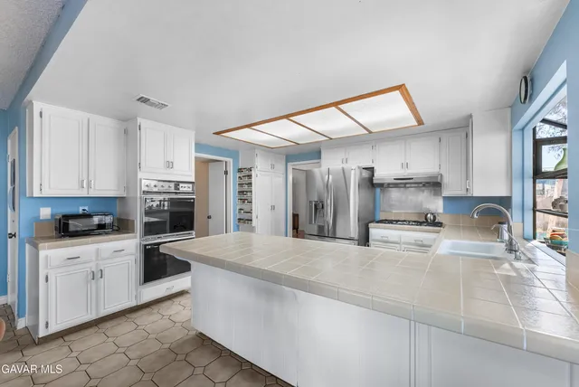 a large kitchen with stainless steel appliances kitchen island granite countertop a sink and cabinets