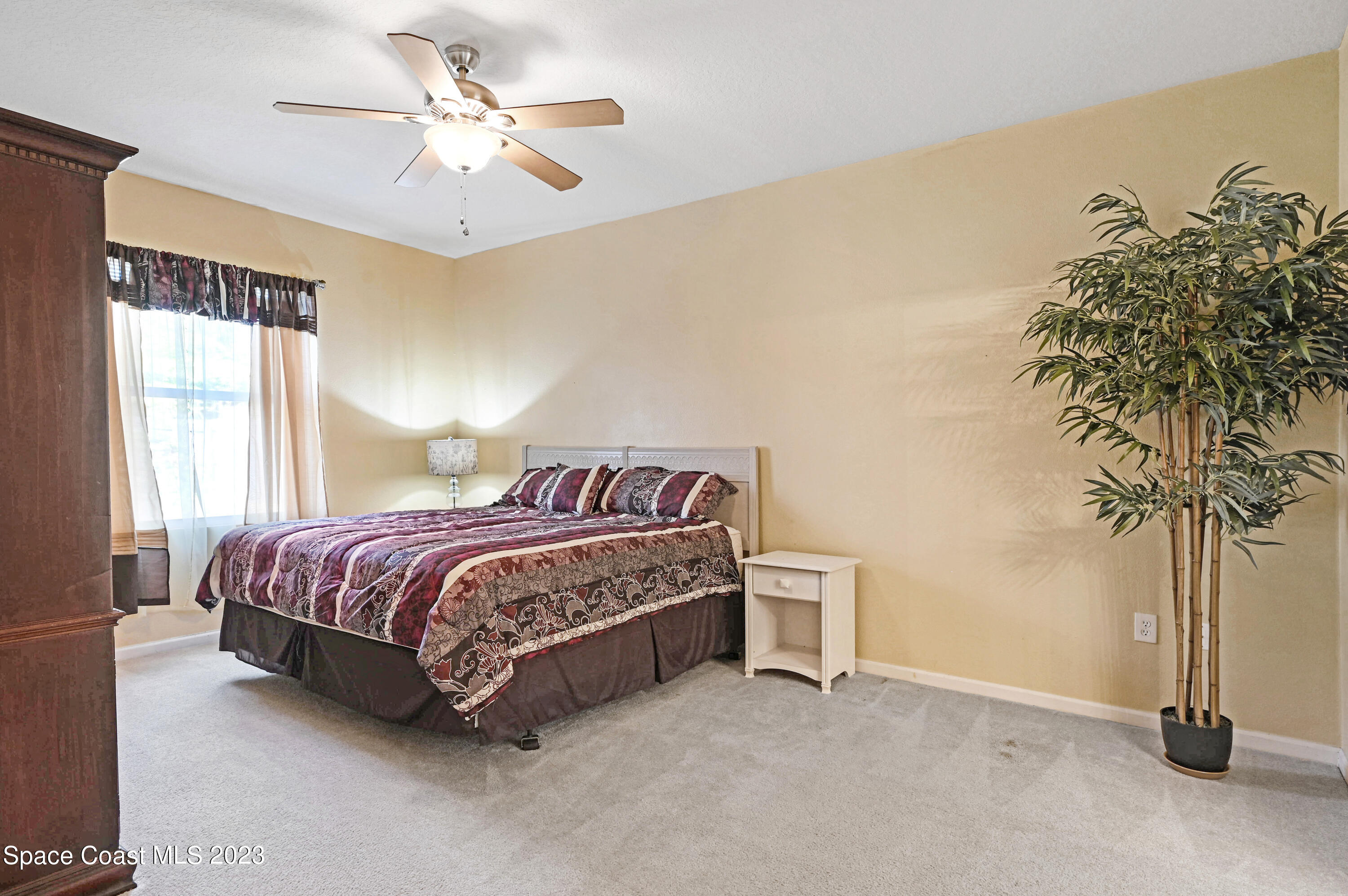 6720 Cairo Road Port St. John, FL 32927 - Photo 10 of 38 a bed sitting in a spacious bedroom next to a window and a chandelier