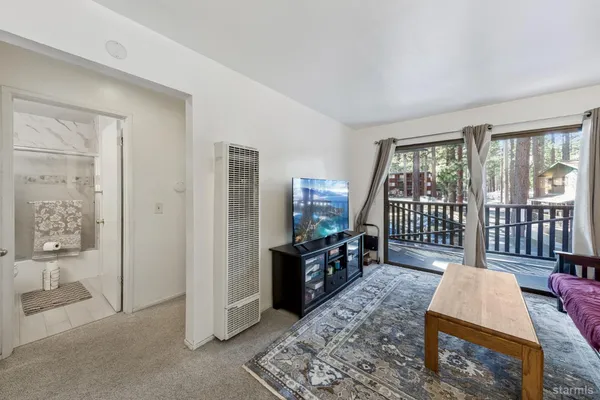 a living room with furniture a flat screen tv and a refrigerator