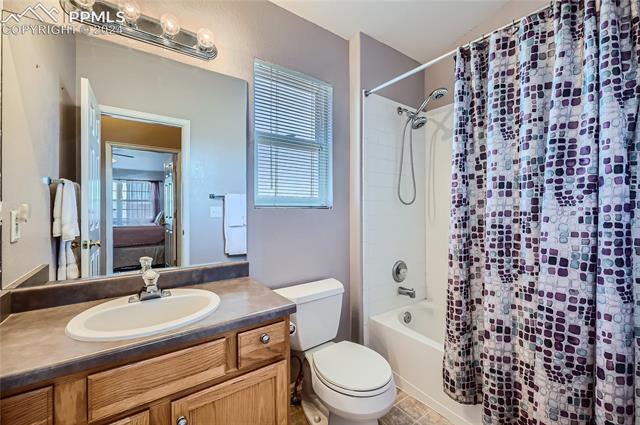 12510 Motley Road Peyton, CO 80831 - Photo 23 of 36 Full bathroom with tile flooring, shower / bath combo, toilet, and vanity with extensive cabinet space