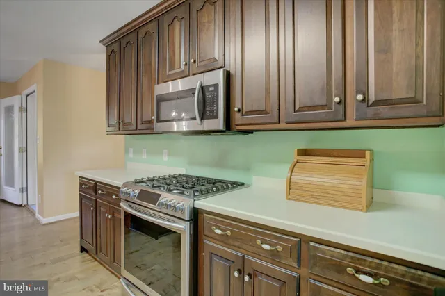 a kitchen with stainless steel appliances granite countertop a stove a sink a microwave a dining table and chairs with wooden floor