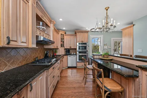 a kitchen with stainless steel appliances granite countertop a stove top oven a sink dishwasher and cabinets with wooden floor