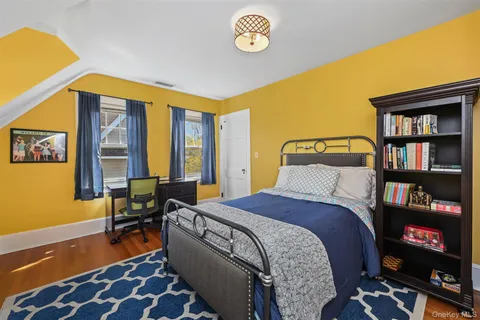 a bedroom with a bed a dresser and a bookshelf with wooden floor