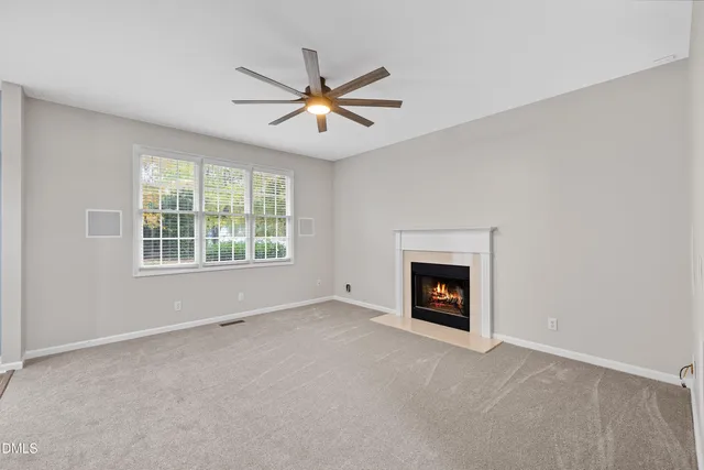 a view of an empty room with chandelier fan and fire place