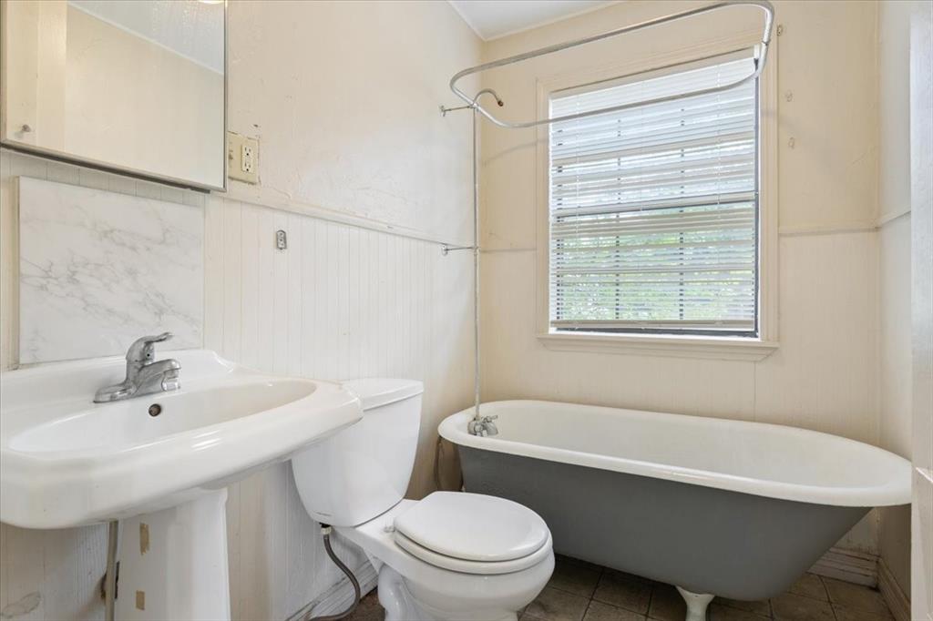 608 9th Street Hico, TX 76457 - Photo 14 of 23 Bathroom featuring a pedestal sink, white toilet, and a clawfoot tub with a shower curtain rod