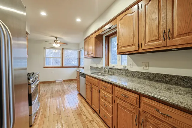 a kitchen with granite countertop a sink a stove cabinets and wooden floor