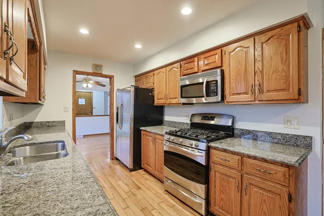a kitchen with granite countertop wooden cabinets a stove top oven and stainless steel appliances