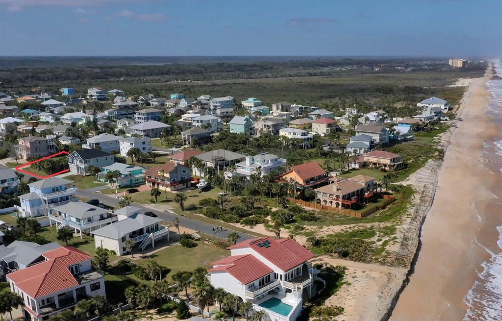 an aerial view of ocean and residential houses with outdoor space