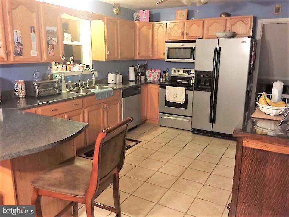 11705 Stoneleigh Road La Vale, MD 21502 - Photo 5 of 13 a kitchen with stainless steel appliances wooden cabinets a stove a sink and a refrigerator
