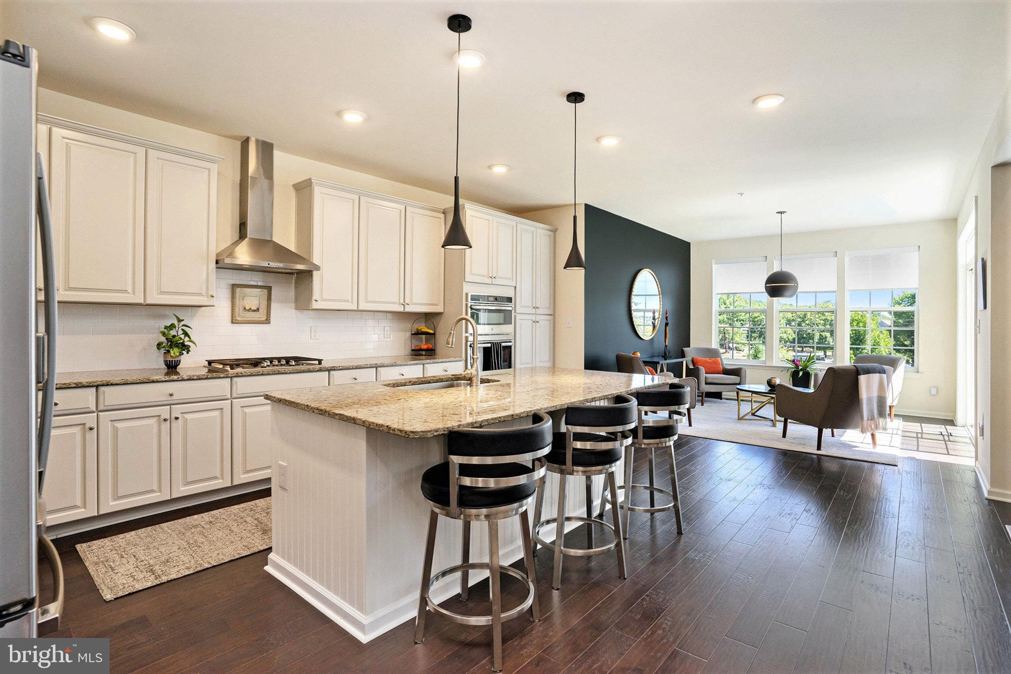 421 Lee Place Exton, PA 19341 - Photo 6 of 58 a kitchen with stainless steel appliances granite countertop a stove a refrigerator a kitchen island a dining table and chairs with wooden floor