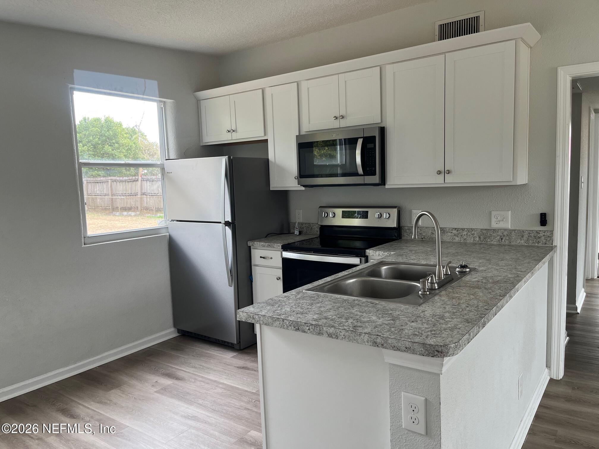 a kitchen with granite countertop a sink stove and refrigerator