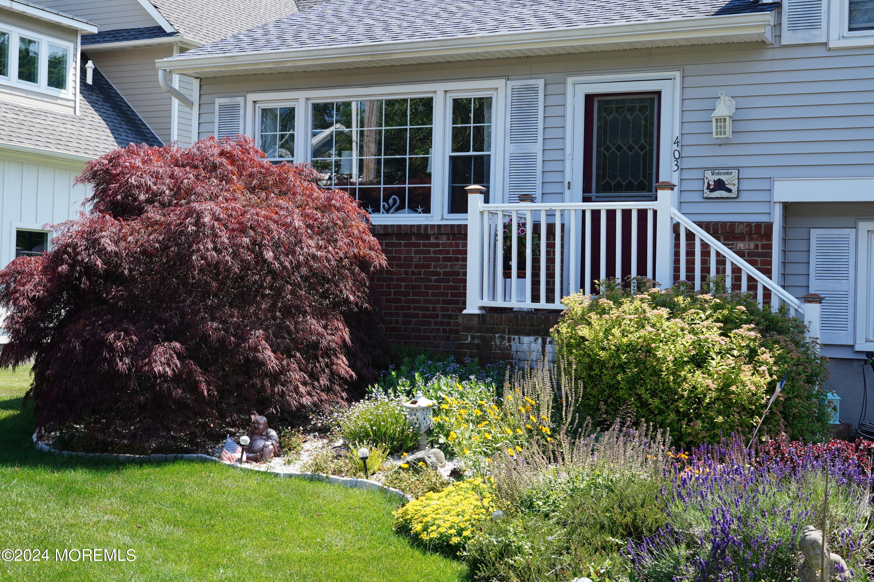 403 Union Lane Brielle, NJ 08730 - Photo 6 of 31 a view of a house with a flower garden and a bench