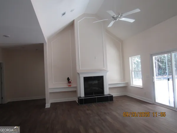 an empty room with windows fireplace and wooden floor
