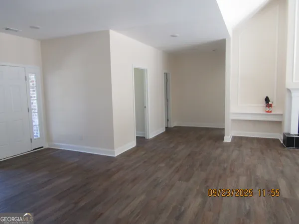a view of an empty room with wooden floor and closet