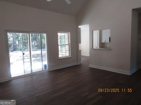 a view of an empty room with wooden floor and a window