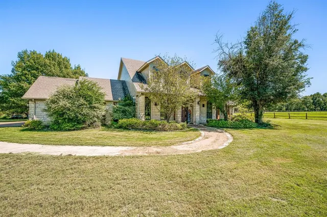 a view of a house with a big yard and large trees