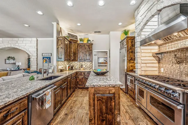 a large kitchen with stainless steel appliances granite countertop a large stove a sink and a refrigerator