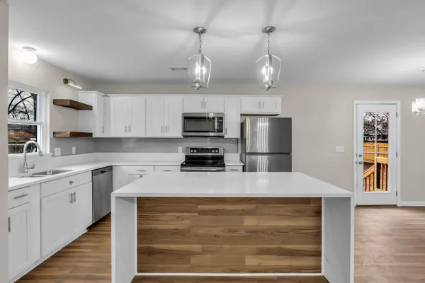 a large kitchen with granite countertop a large counter top space appliances and cabinets