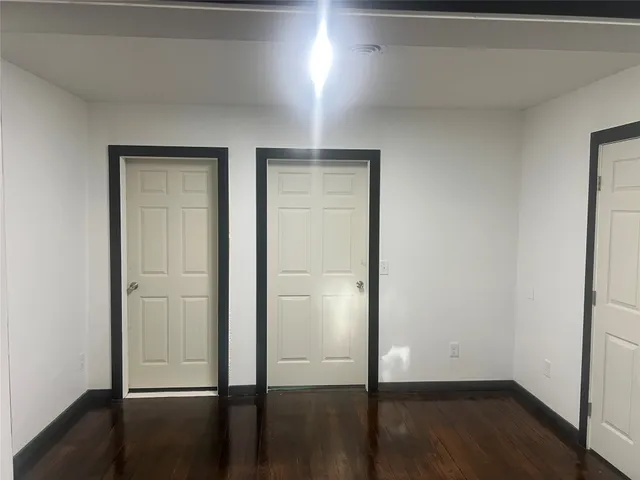 an empty room with wooden floor & closet area
