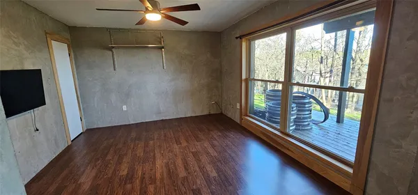 an empty room with wooden floor fan and windows