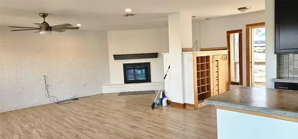 an empty room with wooden floor fireplace and windows