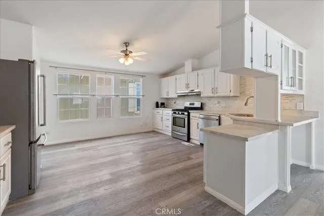 a kitchen with stainless steel appliances granite countertop a stove top oven a refrigerator a sink and dishwasher with white cabinets