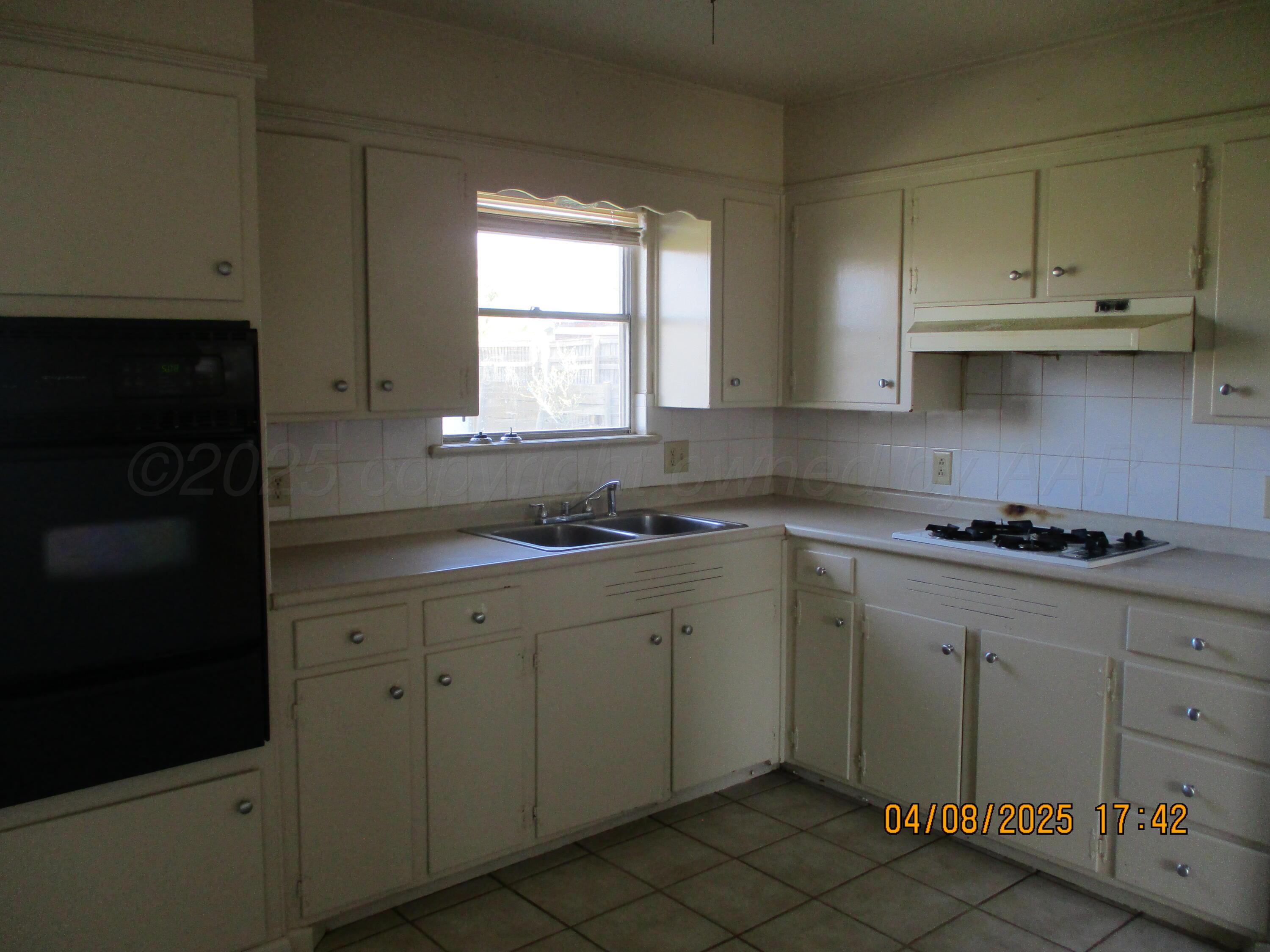 2913 Ricks Street Amarillo, TX 79103 - Photo 3 of 14 a kitchen with cabinets appliances a sink and a window