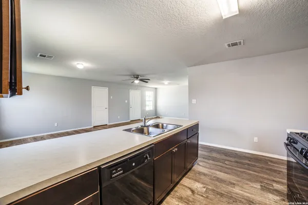 a room with kitchen island a sink a stove and wooden floor