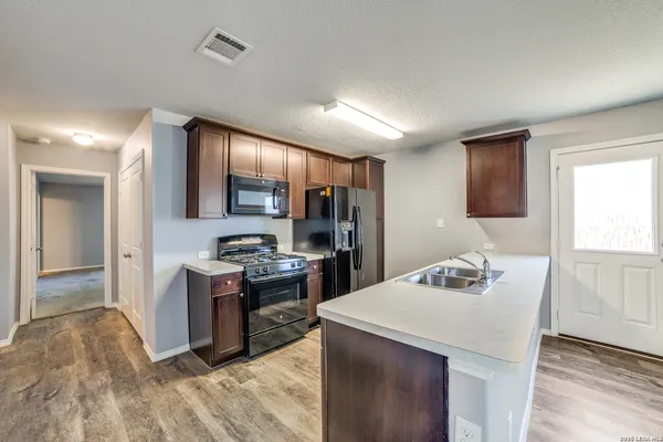a kitchen with kitchen island stainless steel appliances a sink stove and refrigerator