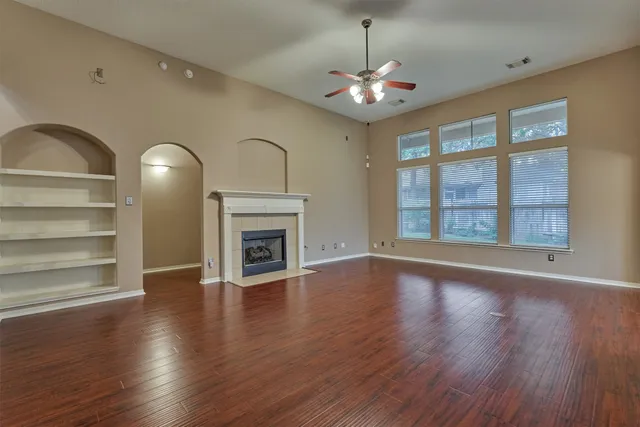 a view of an empty room with wooden floor fireplace and a window