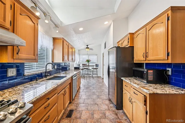 a kitchen with stainless steel appliances granite countertop a stove a sink and a refrigerator