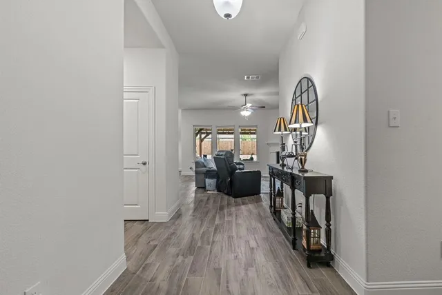 a view of a hallway with wooden floor and a bathroom