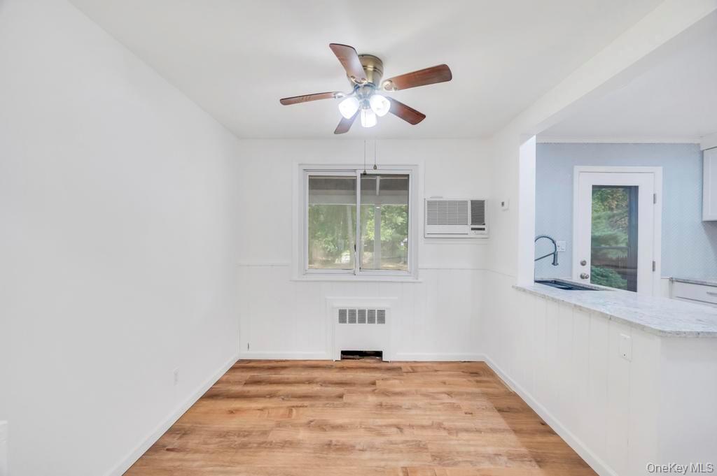 815 Udall Road West Islip, NY 11795 - Photo 11 of 45 Empty room featuring light wood finished floors, a ceiling fan, radiator heating unit, healthy amount of natural light, and a wainscoted wall