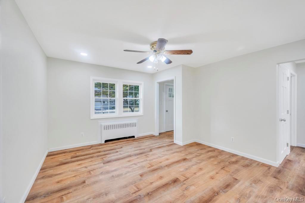815 Udall Road West Islip, NY 11795 - Photo 14 of 45 Empty room with radiator, light wood-style floors, and a ceiling fan