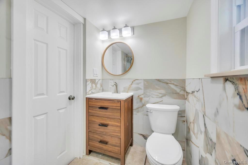 815 Udall Road West Islip, NY 11795 - Photo 17 of 45 Half bath featuring vanity and tile walls