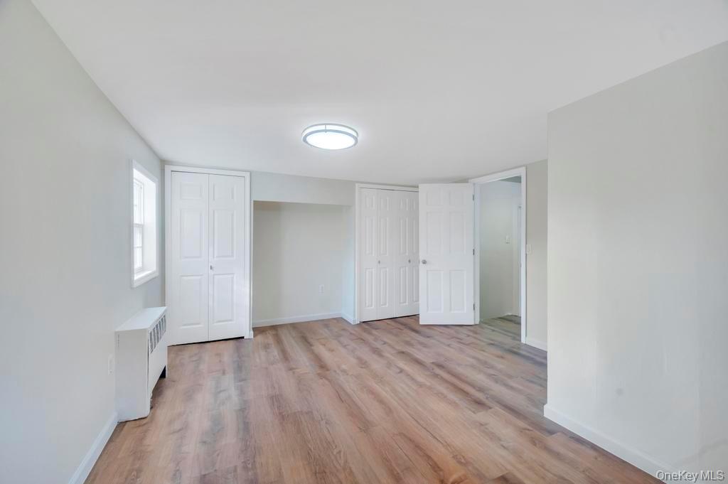 815 Udall Road West Islip, NY 11795 - Photo 22 of 45 Unfurnished bedroom featuring radiator heating unit, light wood finished floors, and two closets