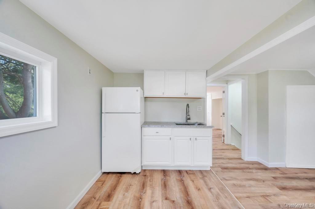 815 Udall Road West Islip, NY 11795 - Photo 26 of 45 Kitchen featuring freestanding refrigerator, white cabinetry, light wood-style floors, and light countertops