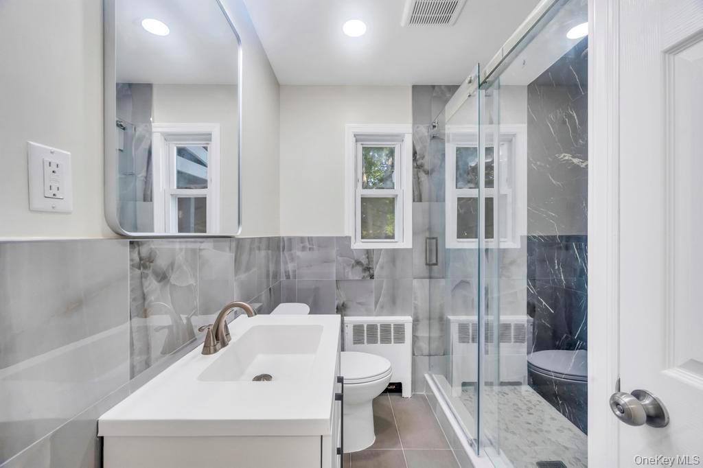 815 Udall Road West Islip, NY 11795 - Photo 28 of 45 Full bathroom with tile walls, radiator, vanity, a shower stall, and tile patterned flooring