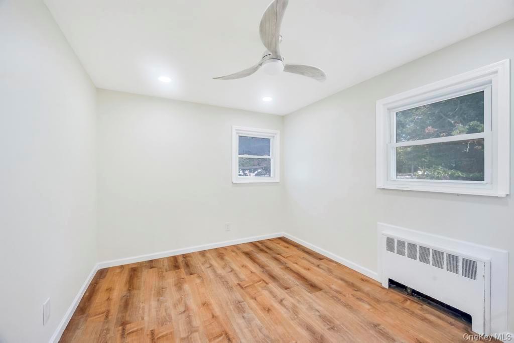 815 Udall Road West Islip, NY 11795 - Photo 33 of 45 Unfurnished room featuring radiator heating unit, light wood-style flooring, a ceiling fan, and recessed lighting