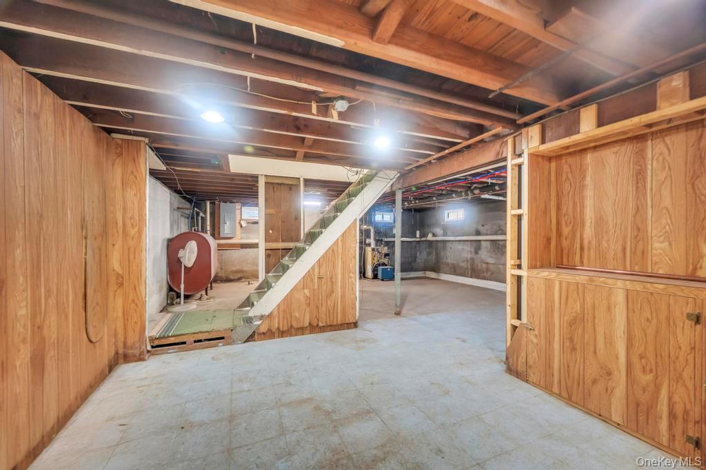815 Udall Road West Islip, NY 11795 - Photo 37 of 45 Unfinished basement with wooden walls, heating fuel, stairway, and electric panel