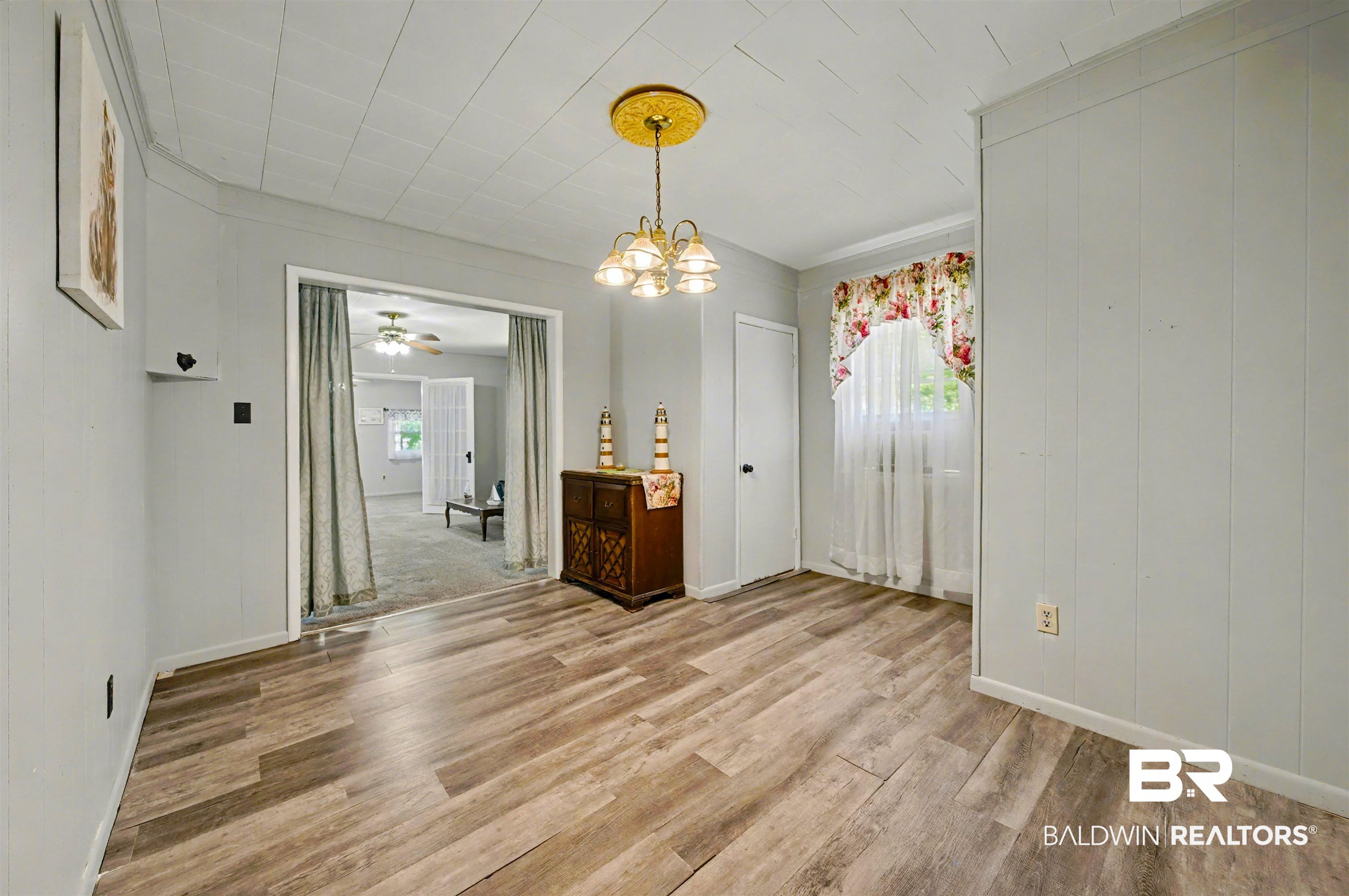 209 West Magnolia Avenue Foley, AL 36535 - Photo 13 of 23 Unfurnished dining area with a chandelier, light wood-style flooring, and ceiling fan