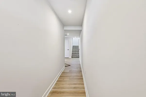 a view of a hallway with wooden floor and a bathroom