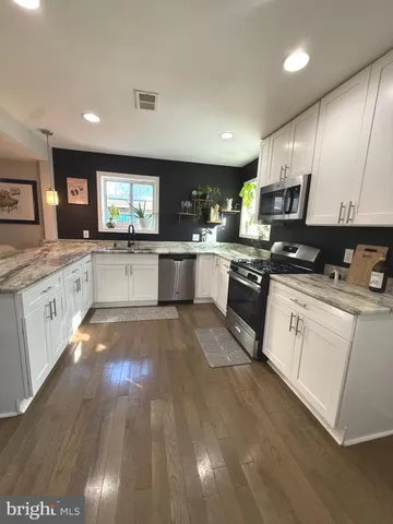 a kitchen with stainless steel appliances granite countertop a table chairs sink refrigerator and microwave