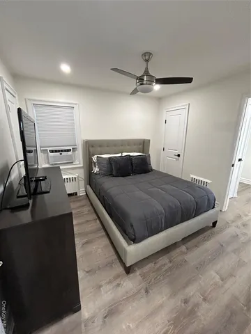 a bedroom with a bed and dresser with wooden floor