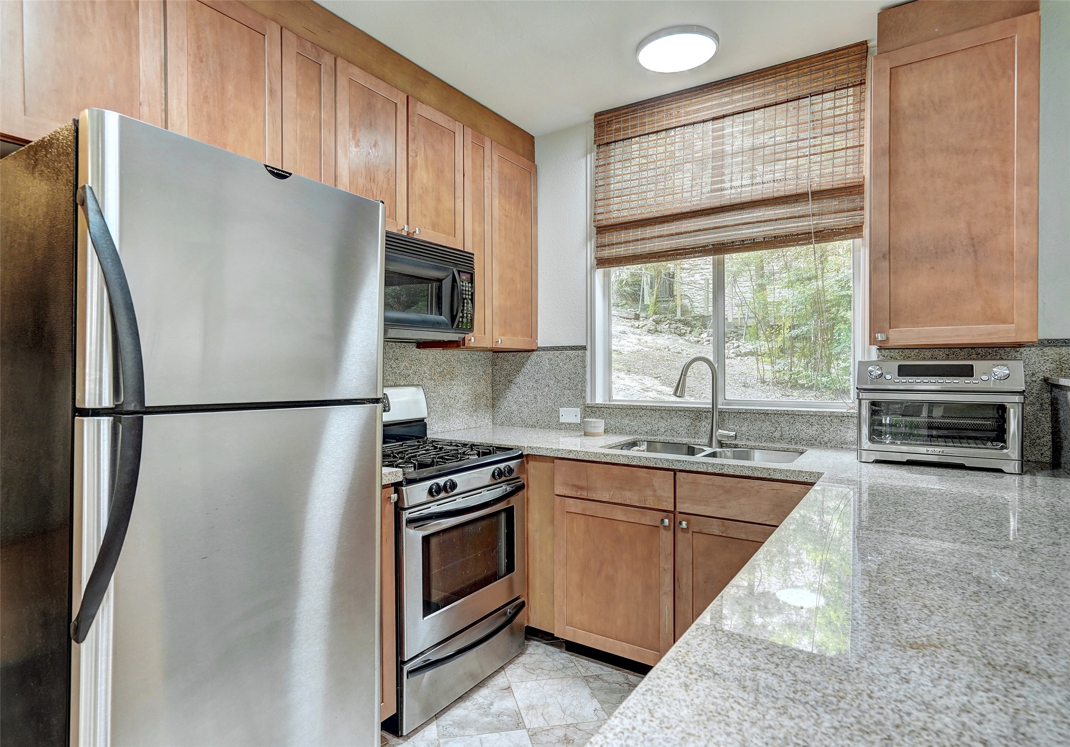 8804 Mountain Ridge Drive, Unit B Austin, TX 78759 - Photo 9 of 17 A well-equipped kitchen offering stainless steel appliances, granite countertops, and light wood cabinetry.